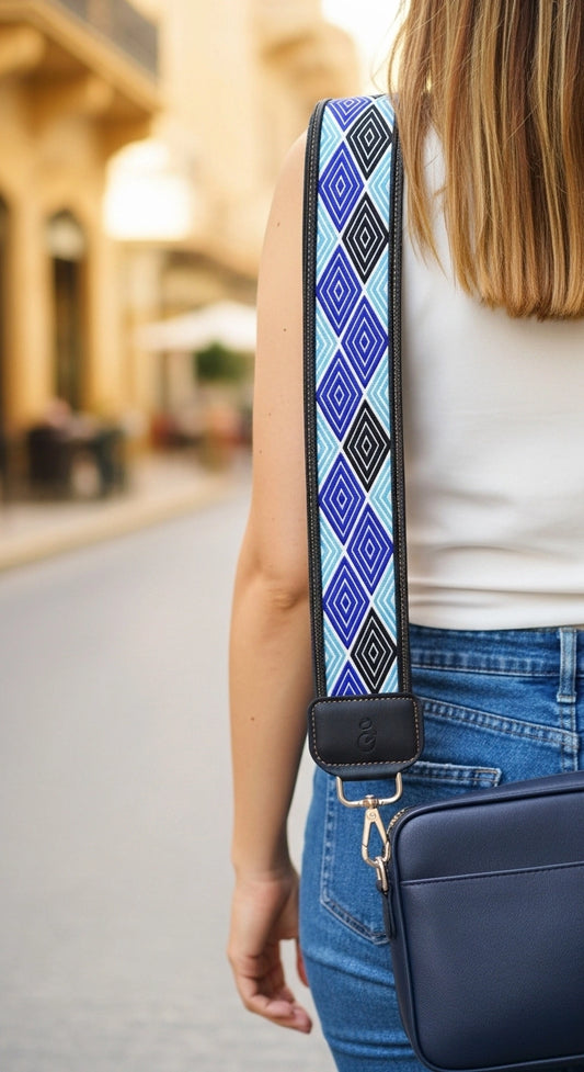 Person wearing a blue bag with a patterned strap on a blurred street background